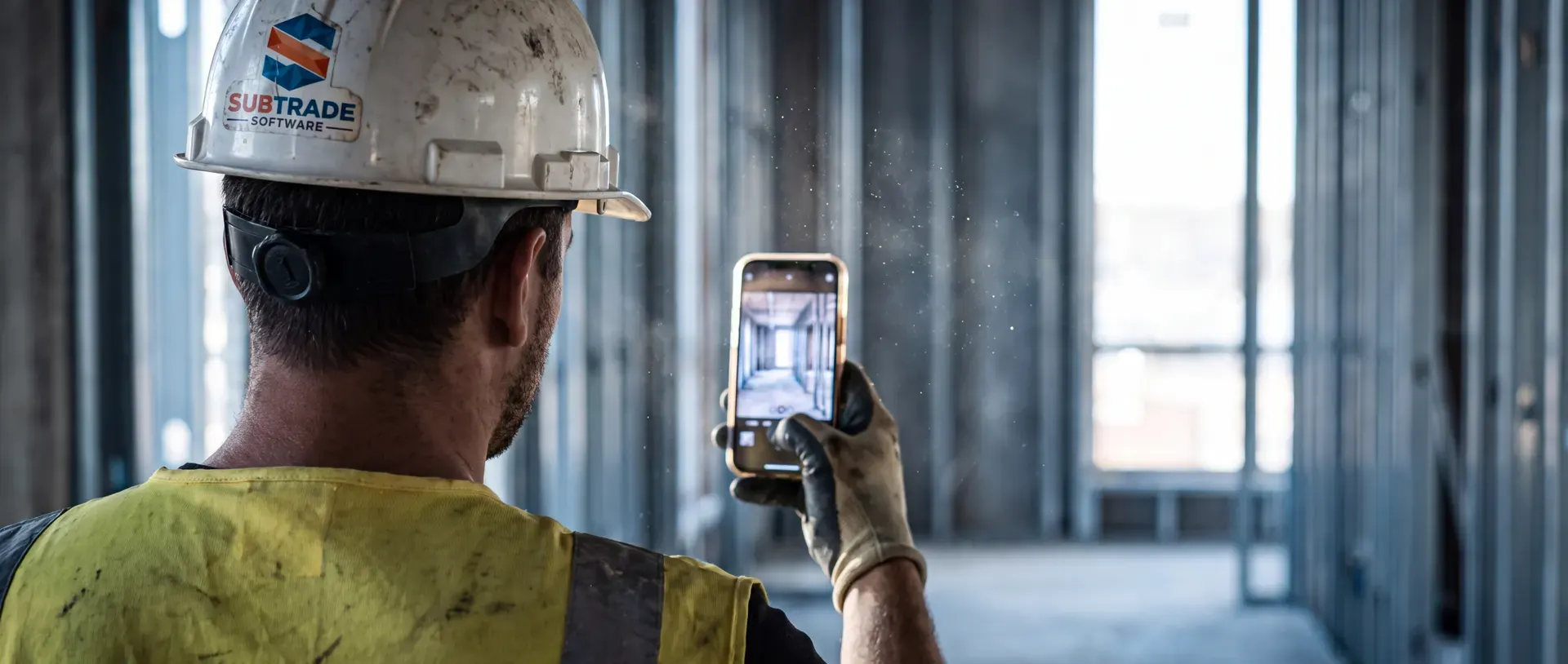Worker in a SubTrade shirt capturing site photos in the SubTrade app